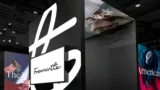 Exhibition booth featuring the Fremantle logo in black and white, with blurred background images of various media content and displays.