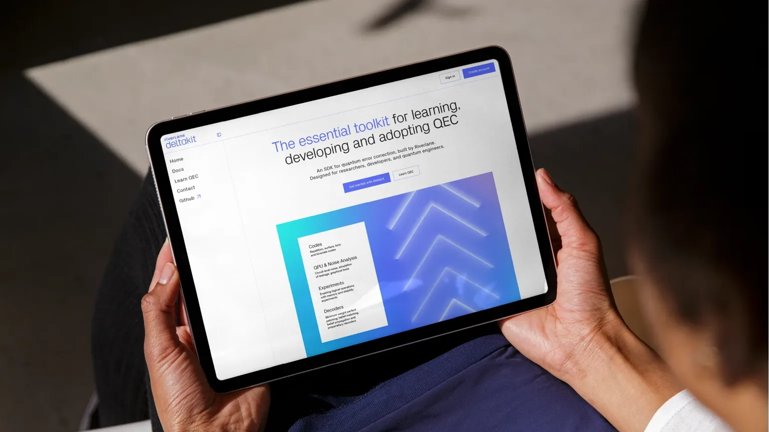 Person holding a tablet displaying Riverlane’s Deltakit website, an SDK for quantum error correction (QEC) with toolkit features listed.