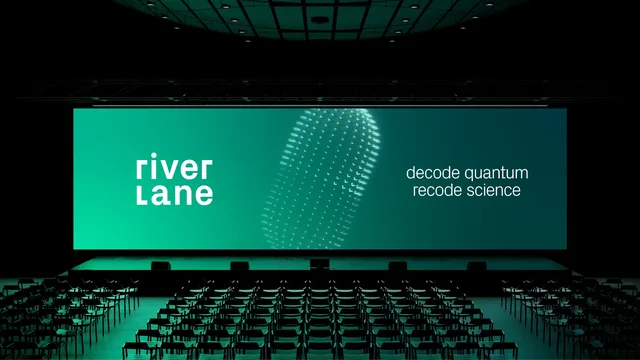 Conference stage with Riverlane branding and the tagline ‘decode quantum, recode the world’ displayed on a large digital screen, rows of chairs in the foreground