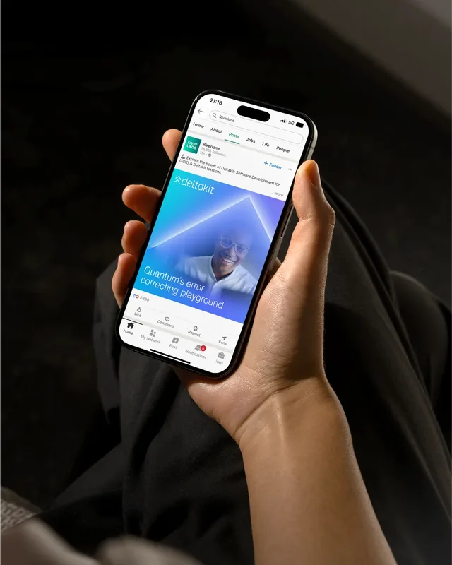 Person holding a smartphone displaying Riverlane’s LinkedIn post about Deltakit, a quantum error-correcting software playground.