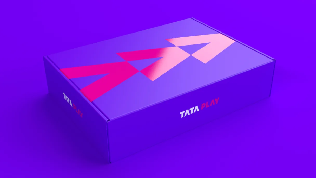 Image showing the Tata Play packaging, featuring the pink arrow logo set against the purple box. All on a purple background.